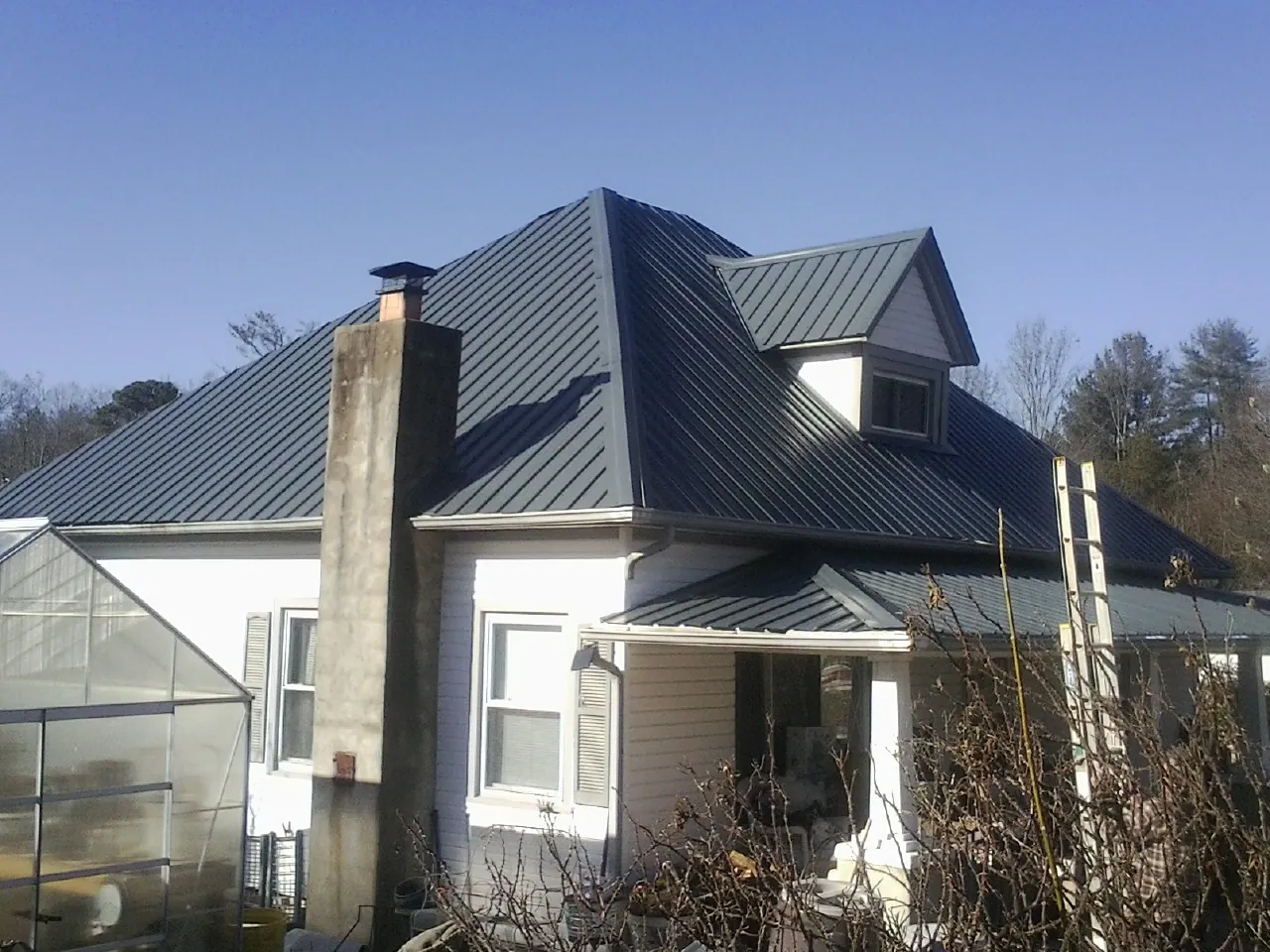 Dark blue standing seam metal roof on a white farmhouse with dormer — Slate & Tile Roof Repair by Roofing Brothers in Waynetown