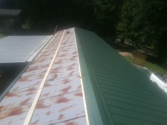 Old rusted panels beside newly installed green metal roofing — Wind Damage Roof Repair by Roofing Brothers in Waynetown