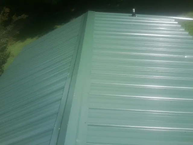 New green metal panels meeting at the ridge of a roof — Flat Roof Repair work by our crew in Waynetown
