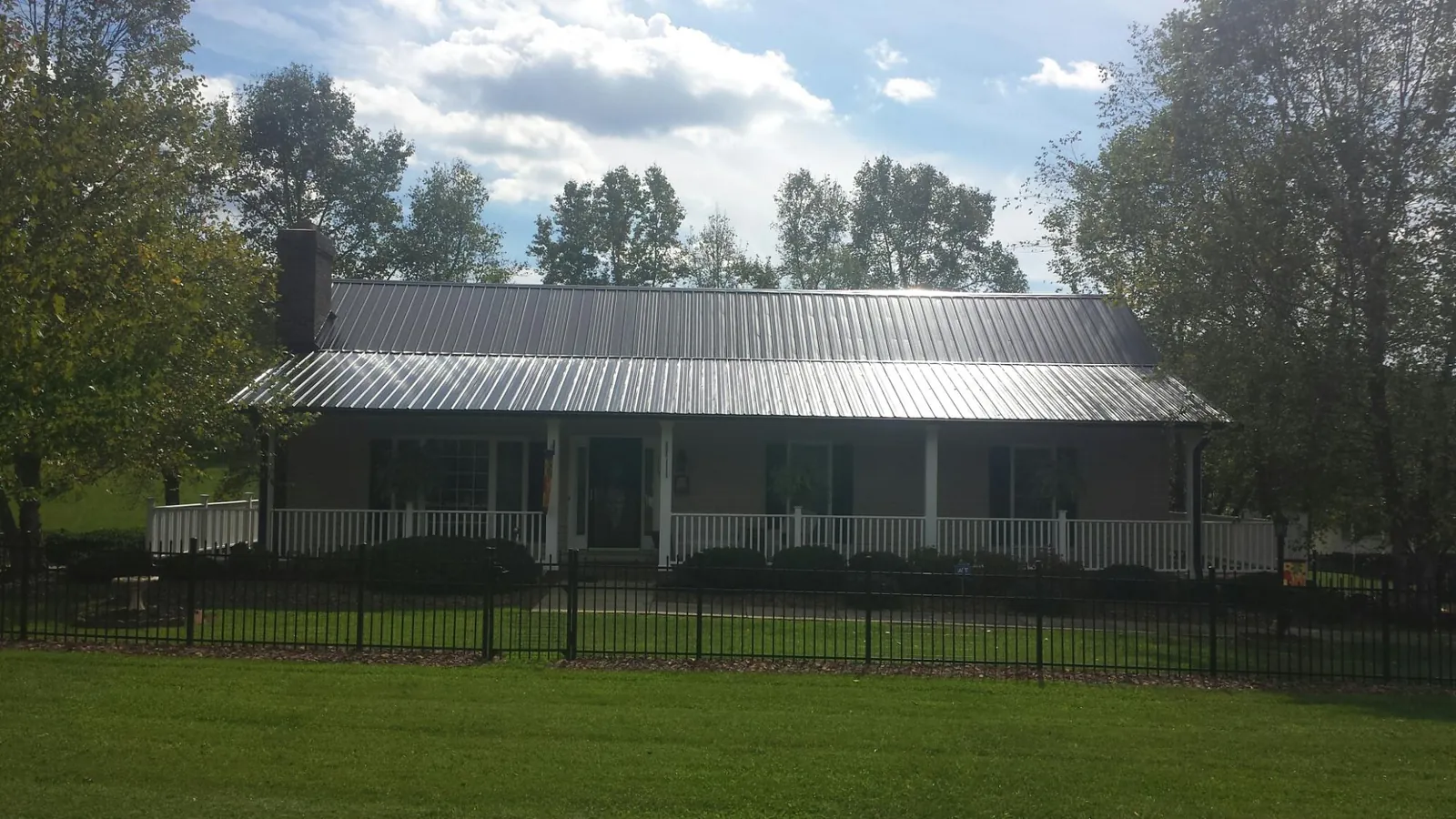 Gray metal roof on a brick ranch with a full width front porch — Gutter Guard Installation work by our crew in Waynetown