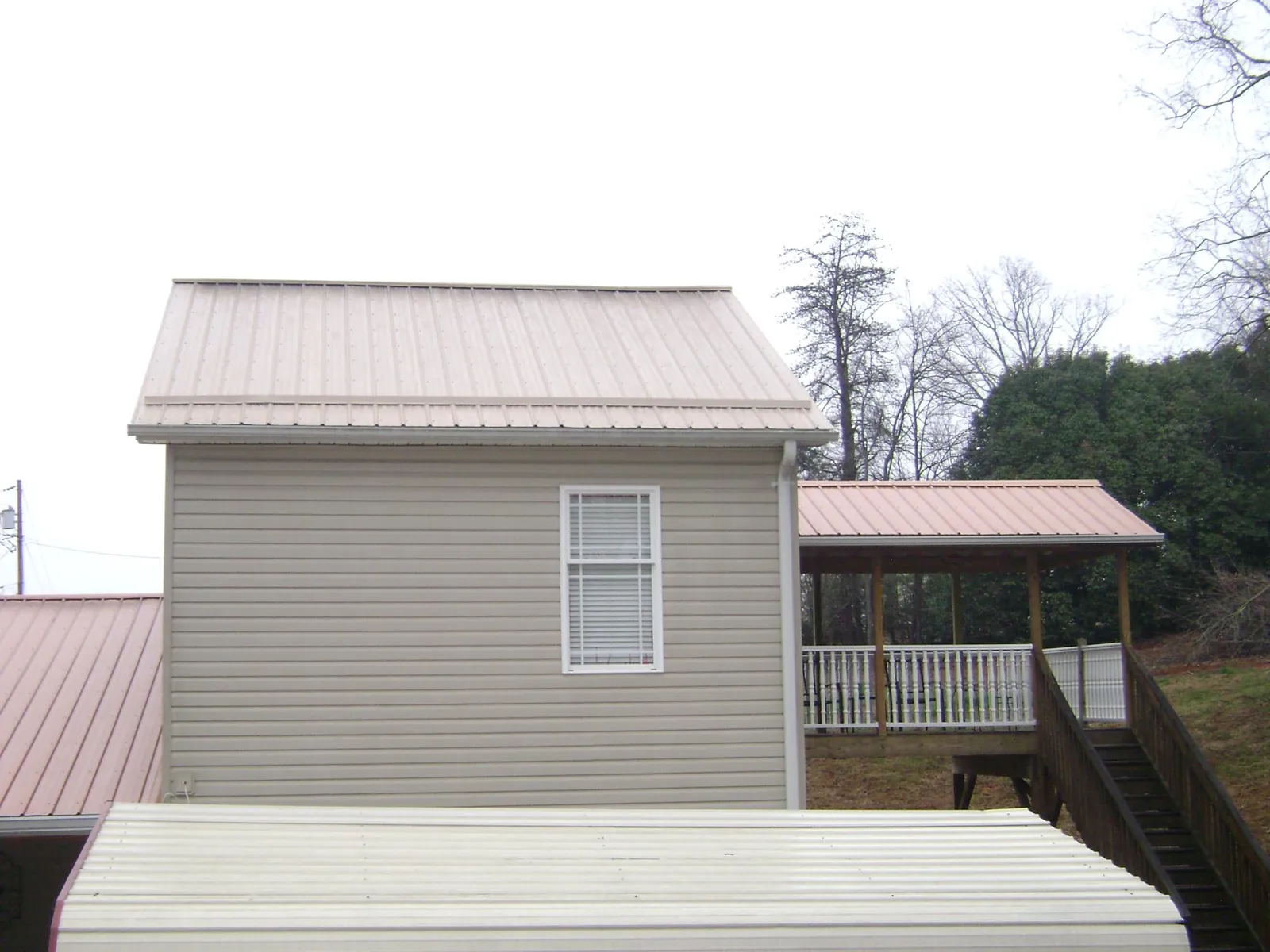 Tan metal roofs on a two story addition and attached porch, from a Roof Replacement job in Waynetown