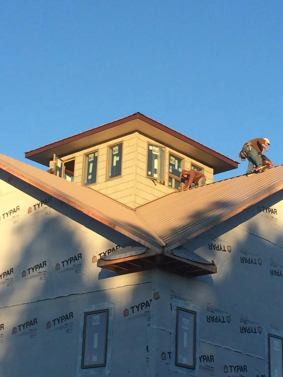 Roofers working around a rooftop cupola on a new metal roof at sunset — Roof Waterproofing in Waynetown by Roofing Brothers